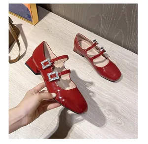 Details von roten Lackleder-Mary-Janes mit funkelnden quadratischen Strass-Schnallen