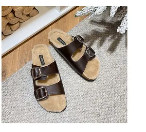 Detail view of brown double-strap slippers with thick faux fur lining and silver buckles