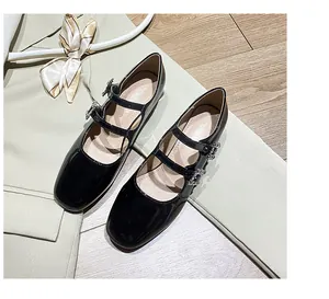 Nahaufnahme schwarzer Lack-Mary-Janes mit doppelten Riemen und Strass-Schnallen