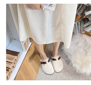 Close-up of beige fleece Birkenstock clogs with brown strap on a warm home carpet