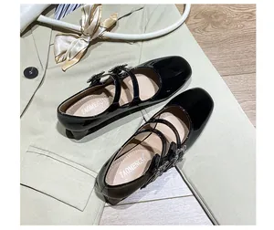 Draufsicht auf schwarze Lackleder-Mary-Janes mit Strassschnallen auf grünem Blazer