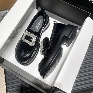 Glossy black patent leather platform loafers with sparkling rhinestone buckle in shoe box