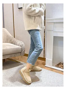 Close-up of beige leather snow boots with platform sole in a cozy indoor setting