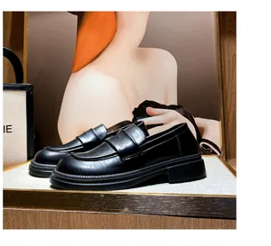 Detalle de mocasín de plataforma en cuero negro brillante con correa y suela dentada