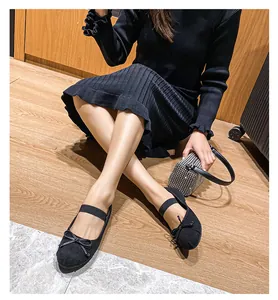 Dettaglio di ballerine nere con fiocco e cinturino elastico su pavimento in legno