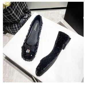 Dettaglio scarpe basse eleganti con paillettes nere, fiocco di strass e suola spessa