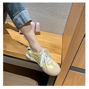 Close-up of beige and yellow leather trainers on model with pink chain bag