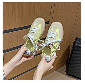 Close-up of yellow and beige leather trainers featuring classic rubber soles and HZ heel pull tabs