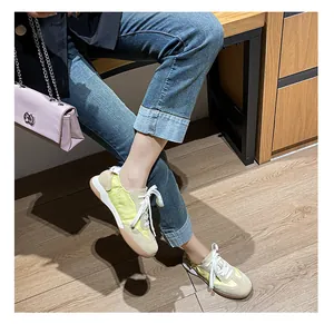 Detail of ballet style leather trainers in beige and neon green on model with wood background