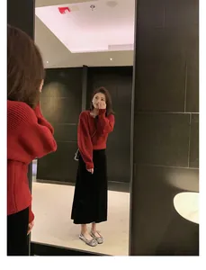 Dettaglio di maglia rossa a trecce abbinata a gonna nera e scarpe piatte argentate