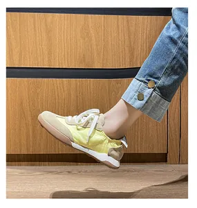 Detailed side view of yellow leather ballet sneakers with embroidery on wood background