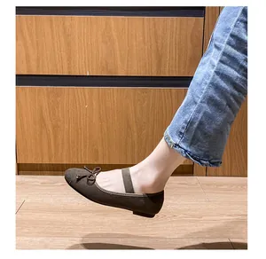 Dettaglio di ballerine Mary Jane marroni con cinturino elastico e fiocco indossate