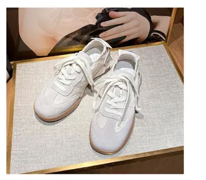 Detail view of cream white leather sports sneakers with suede texture and gum rubber soles