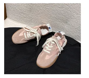 Close-up of pink suede ballet sneakers with thick white laces and gum rubber soles