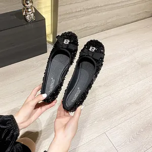 Women's black sequin ballet flats with bow and crystal B buckle on wooden floor