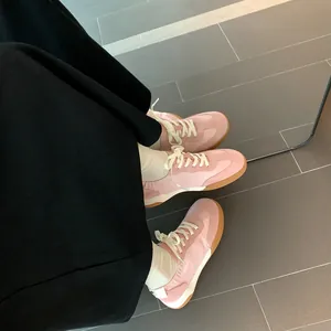 Women's pink leather Samba sneakers with gum sole worn with white socks and a black skirt