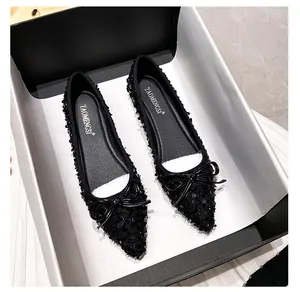 Detail view of black sequin flat shoes with delicate bow and pointed toe in a box