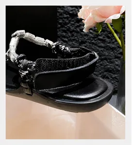 Detail of adjustable hook-and-loop heel strap with shiny rhinestone chain on black sandals