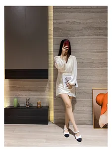 Détail de robe blanche en satin à manches longues bouffantes et jupe croisée