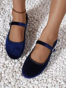 Detail of dark blue velvet Mary Jane flats with silver buckle strap on white pebbles