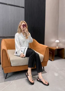 Fashionable black flip-flops with metal chain detail paired with white shirt and wide trousers