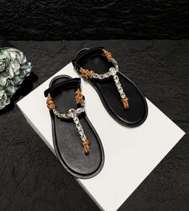 Detail of flat flip-flops with crystal T-strap design and brown braided rope knots
