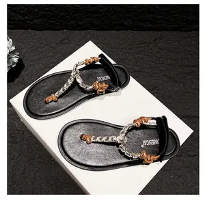 Detail view of flip-flop sandal with sparkling rhinestone chains and knotted rope straps