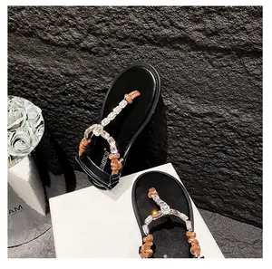 Detail of black flip-flop sandals with rhinestone chains and woven rope straps