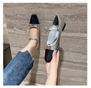 Detailed close-up of two-tone Mary Jane flats with silver metallic and black satin toe
