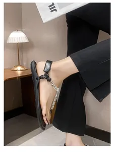 Detail of black leather flat sandals with sparkling crystal T-strap and ankle strap
