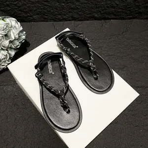 Flat thong sandals with black and white braided rope straps and adjustable heel velcro