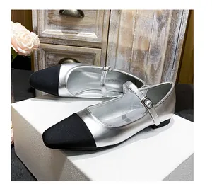 Detail of silver Mary Jane flats featuring a black square toe and elegant strap buckle