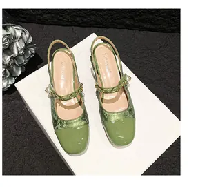 Draufsicht auf grüne Mary-Jane-Mules mit Perlendetails und Metallkette auf Jacquard-Stoff
