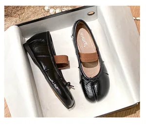 Detailed top view of black leather Tabi flats with elastic strap and small bow decoration