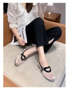 Close-up of white breathable mesh Mary Jane flats with black patent leather trim detail