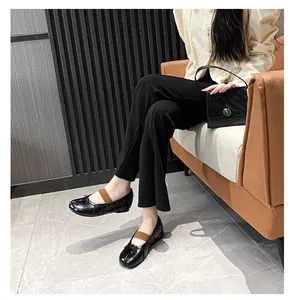 Detail of black Tabi flats with leather finish, bow detail and brown elastic ankle straps
