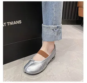 Detail shot of metallic silver Tabi flat shoes with bow and brown elastic strap