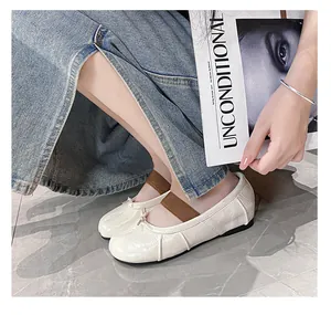 Top-down view of cream sheepskin Tabi flats with bow and elastic band on marble floor