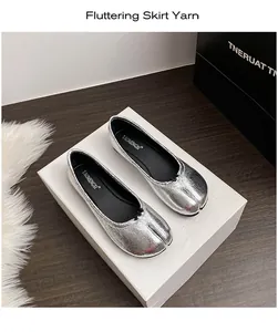 Detail view of silver metallic Tabi flats with unique cracked texture on textured white box