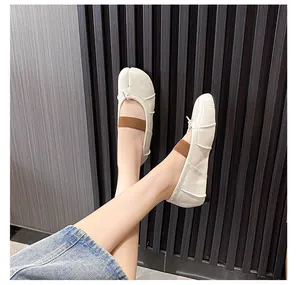 Detailed close-up of cream Tabi ballet flats with brown elastic strap and bow detail