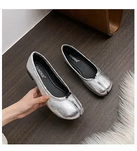 Detail showing metallic silver Tabi flat shoe with crinkled texture and small black bow