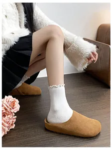Detail of camel suede mule slippers paired with white ribbed ruffle edge socks