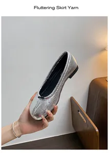 Detail of silver metallic ballet flats with black bow and elegant textured finish