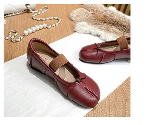 Detail of burgundy Tabi flat shoes with split-toe design and elastic strap on a desk