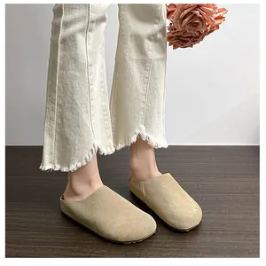 Close-up of beige suede mule shoes with thick soles worn with casual frayed hem trousers