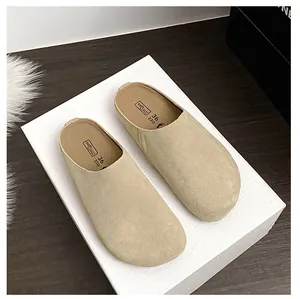 Close-up of soft beige suede mules featuring branded cushioning and comfortable sole