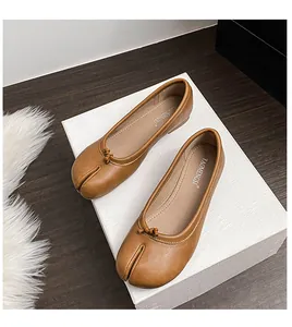 Close-up of brown leather Tabi flat shoes with split-toe design and bow tie detail