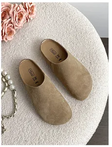 Top view of brown suede mule clogs with ergonomic soft footbed on cozy white texture