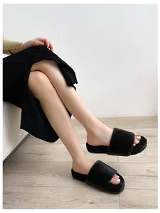 Close-up of black faux fur slide slippers worn by a model in a cozy indoor setting