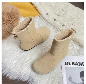 Nahaufnahme beiger Wildleder-Schneestiefel mit flauschigem Innenfutter auf weichem Teppich